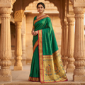Woman in a green saree with gold border standing in an architectural setting