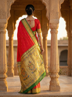 Woman in a red and gold saree standing in an architectural setting