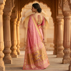 Woman in a pink saree standing in an architectural setting with intricate columns.