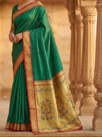 Green saree with gold border and patterns draped over a person, set against an architectural background.