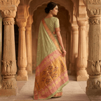 Woman in a traditional saree standing in an architectural setting with ornate columns.