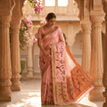 Woman in a traditional saree standing in an architectural setting with floral decorations.