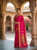 Woman in a pink saree with gold patterns standing in an architectural setting.