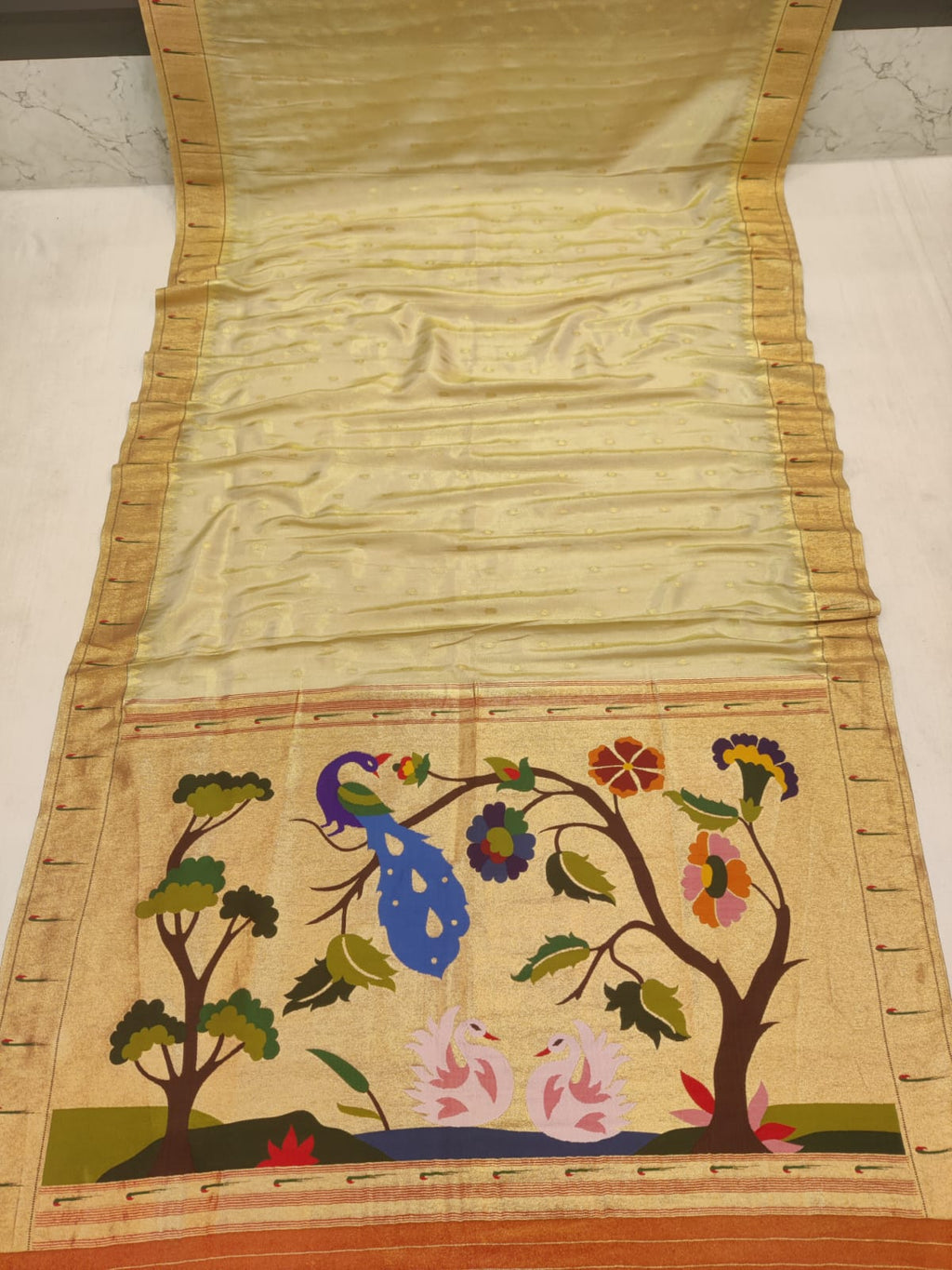 Embroidered fabric with floral and peacock design on a plain background