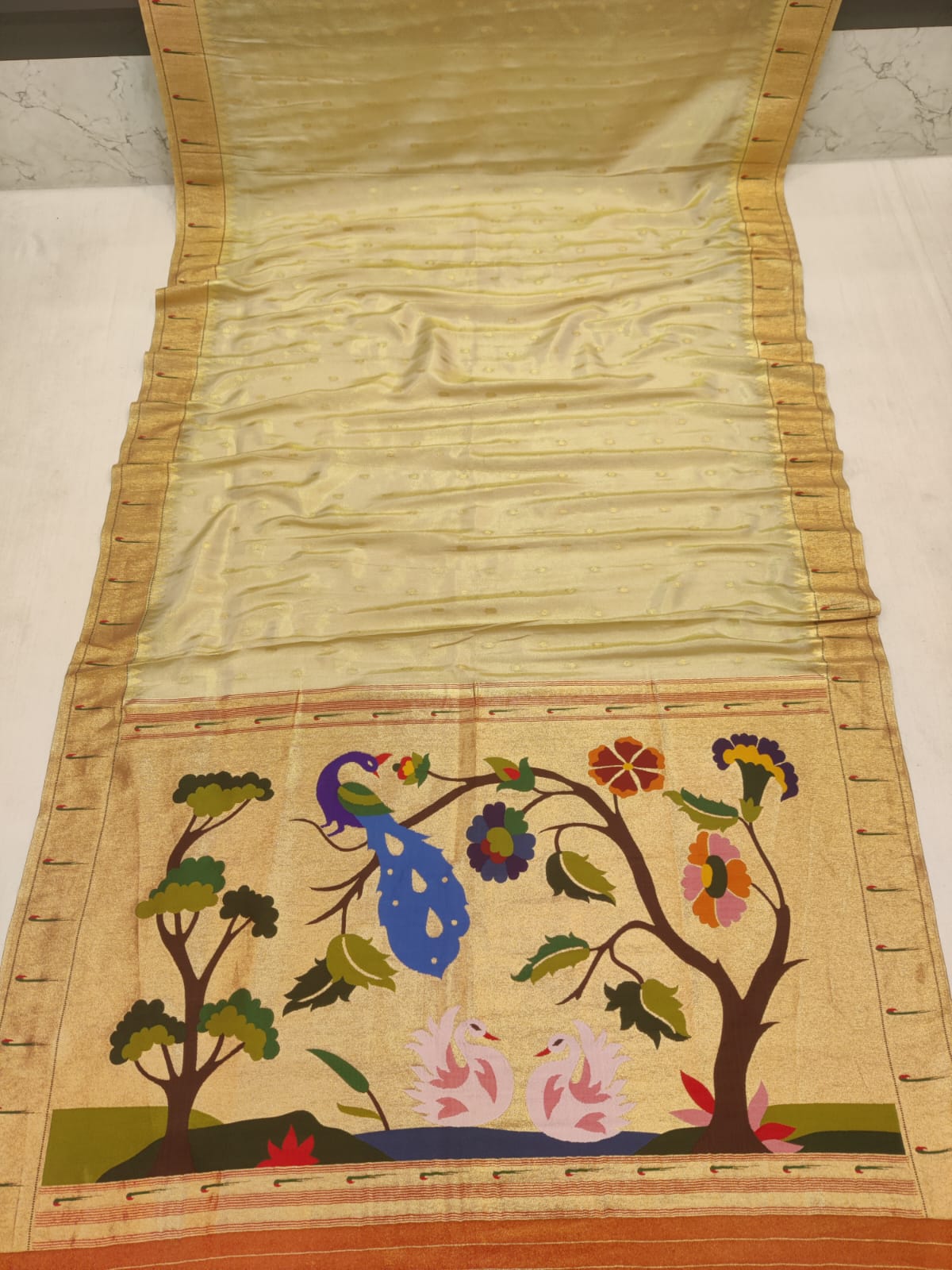 Embroidered fabric with floral and peacock design on a plain background