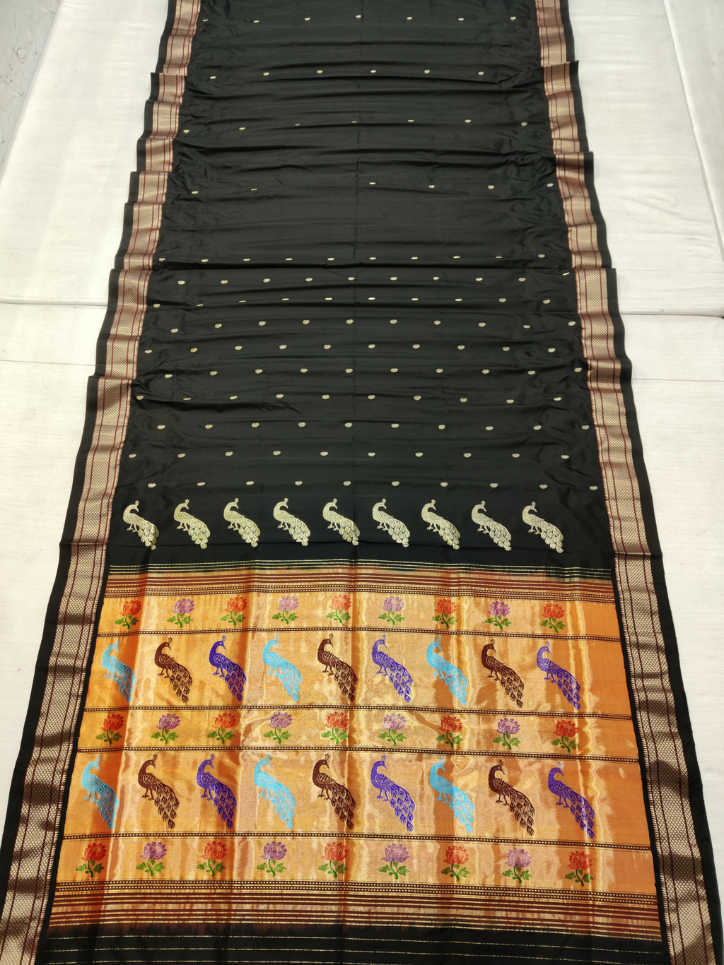 Black saree with colorful peacock and floral patterns on a white background