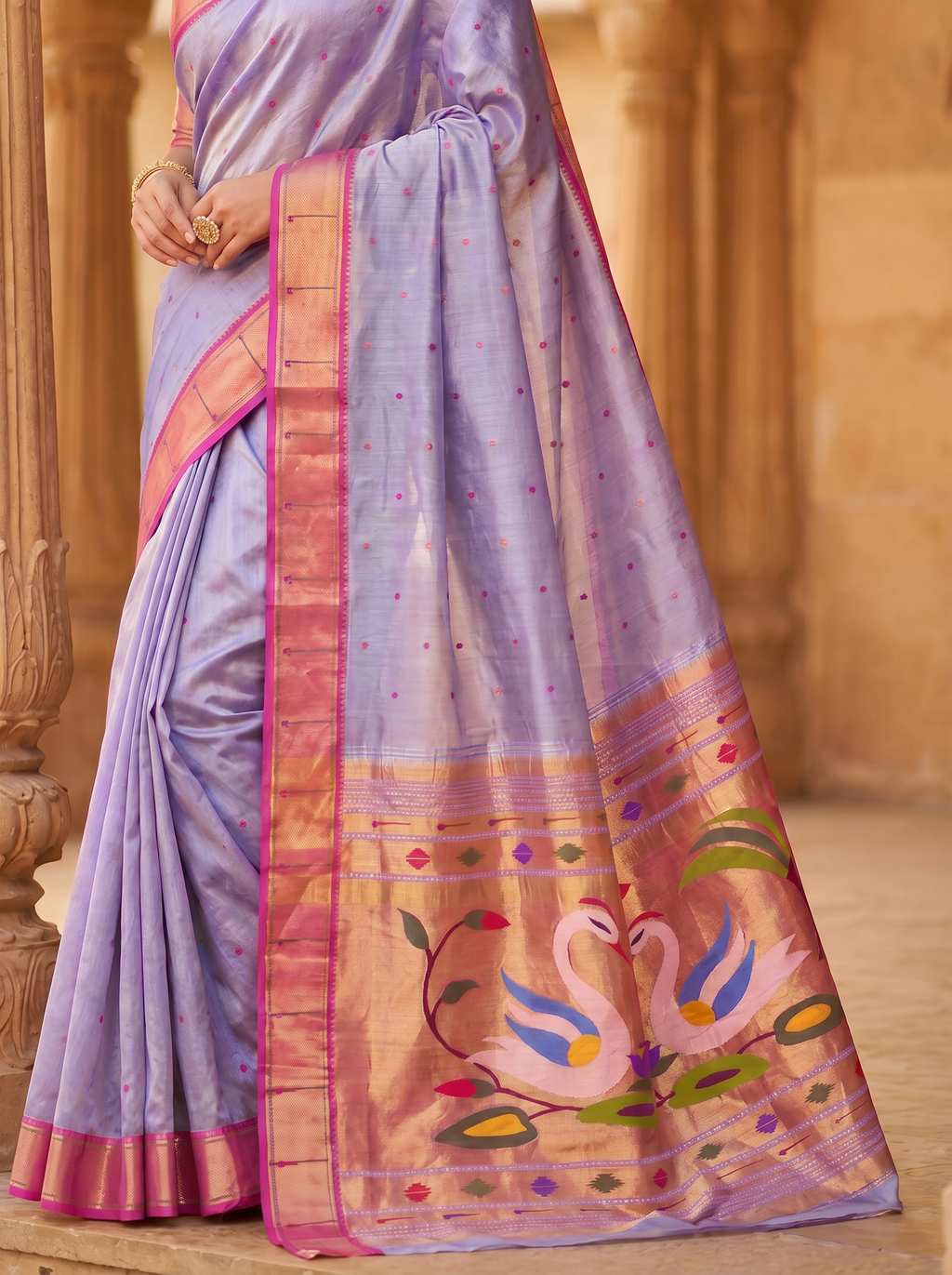 Purple saree with pink border and swan design in a warm-toned setting
