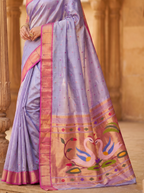 Purple saree with pink border and swan design in a warm-toned setting